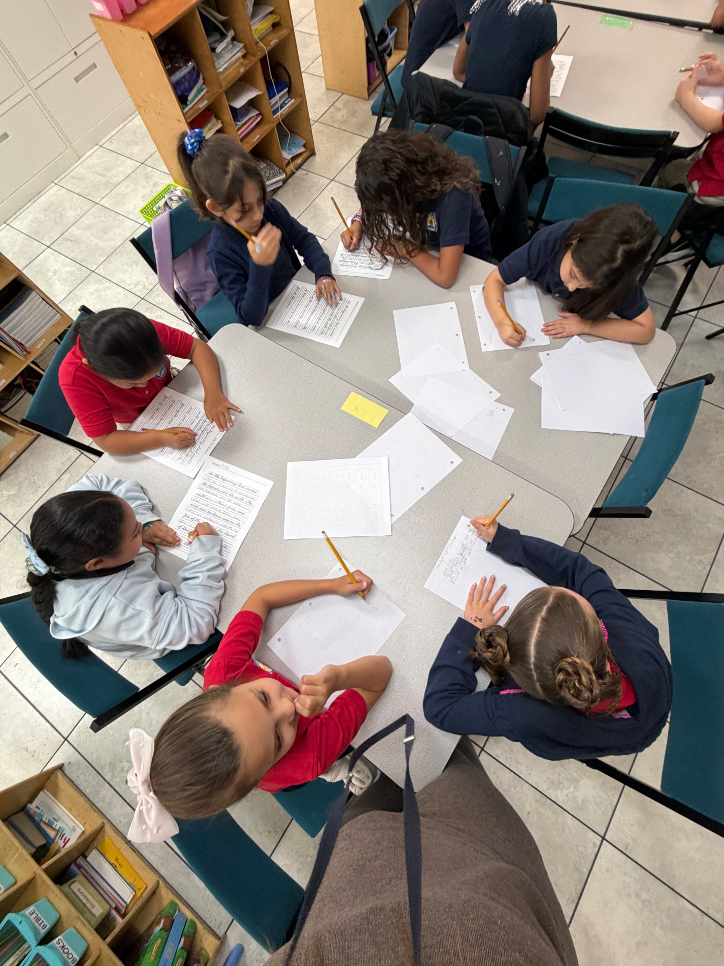 Group of students writing and working together at a table at Growing Together Academy